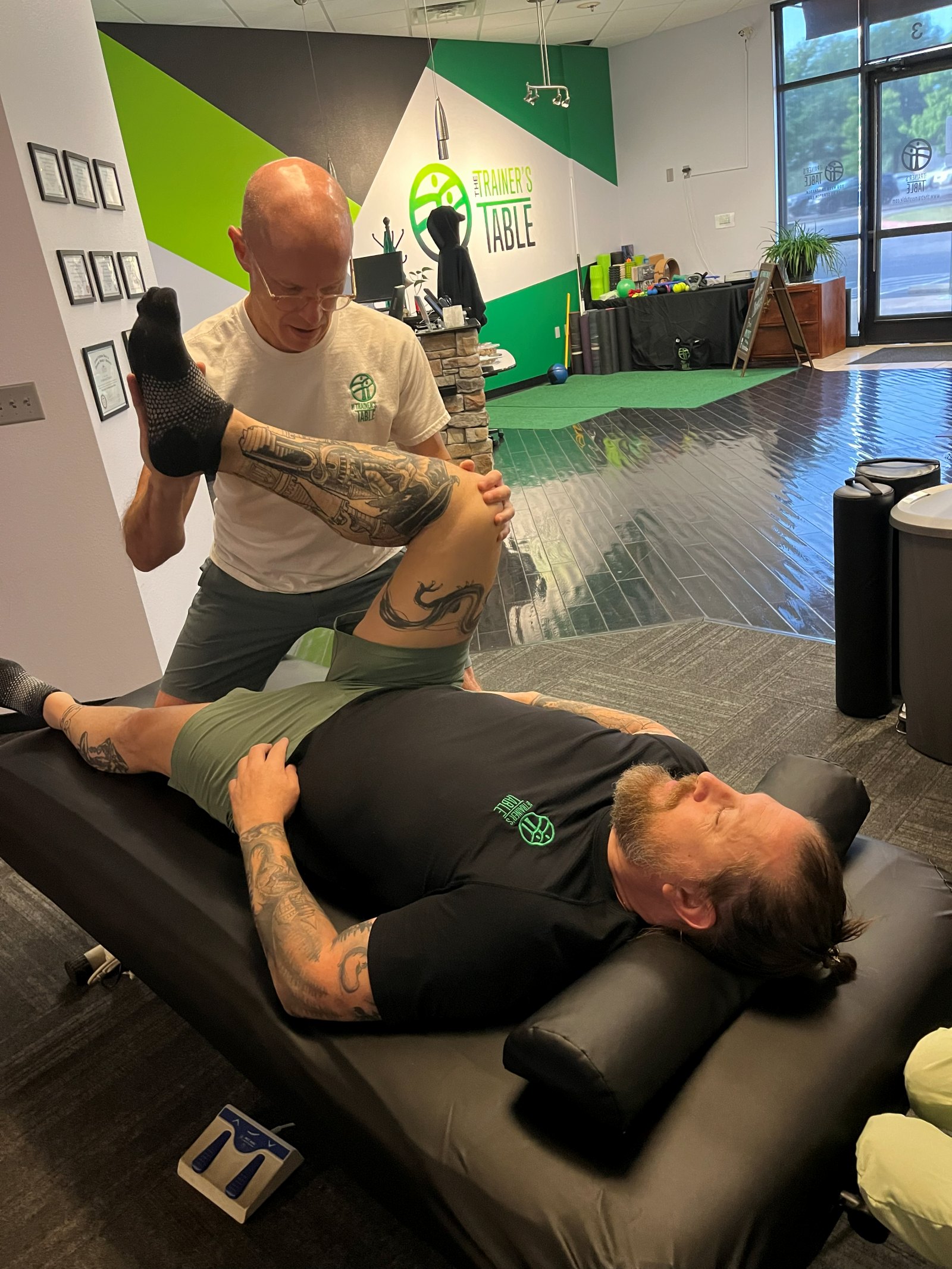 A Licensed Massage Therapist guiding Patrick through an assisted leg stretch